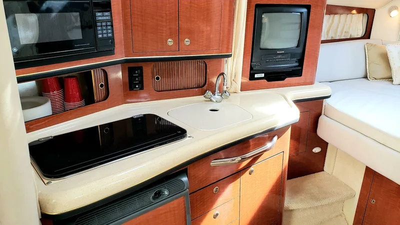 Slide: The Image of 2002 Sea Ray 300 Sundancer interior with kitchenette, microwave, and cozy seating area. - 16