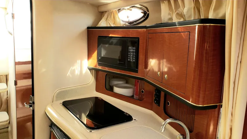 Slide: The Image of 2002 Sea Ray 300 Sundancer kitchen with microwave, stove, and wooden cabinetry. - 17