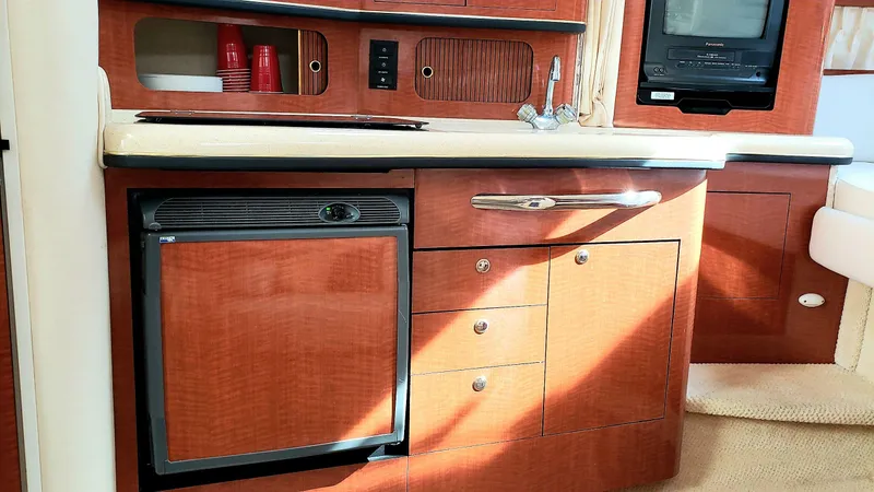 Slide: The Image of 2002 Sea Ray 300 Sundancer interior kitchen with wood cabinetry and compact appliances. - 18