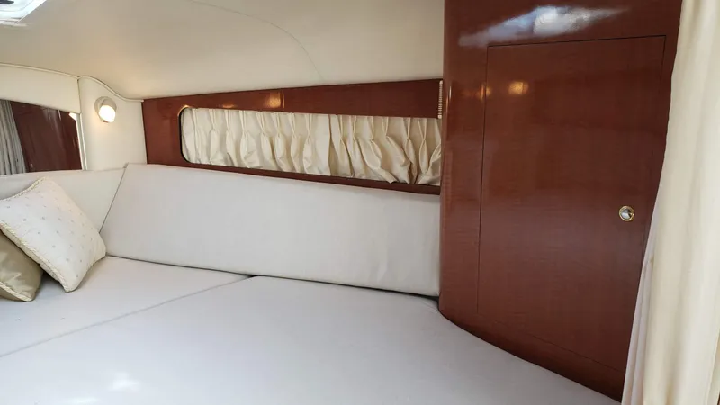 Slide: The Image of Interior cabin of 2002 Sea Ray 300 Sundancer with white cushions and wood paneling. - 24