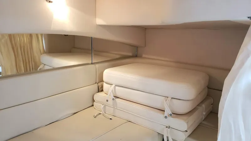 Slide: The Image of Interior cabin of 2002 Sea Ray 300 Sundancer with stacked cushions and beige upholstery. - 26
