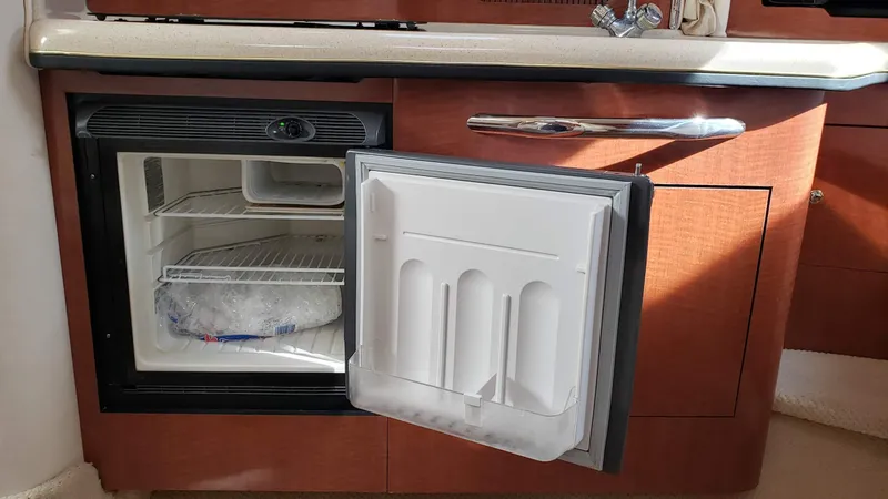 Slide: The Image of Mini fridge in 2002 Sea Ray 300 Sundancer yacht kitchen, open door showing interior shelves. - 28