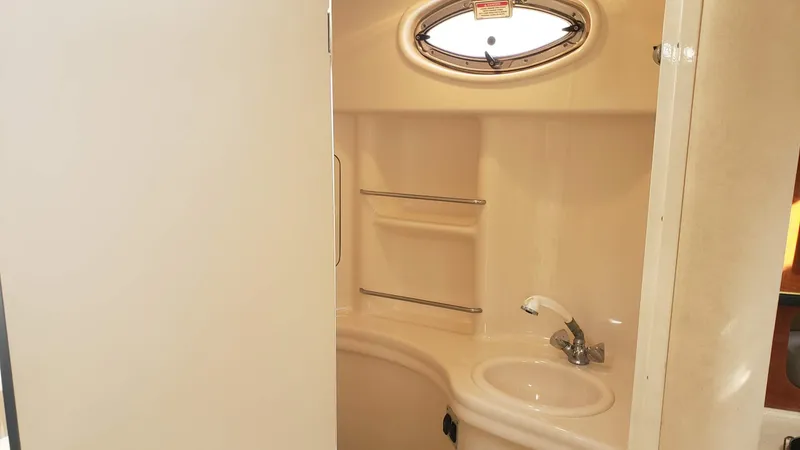Slide: The Image of 2002 Sea Ray 300 Sundancer bathroom with sink, oval window, and storage shelves. - 29