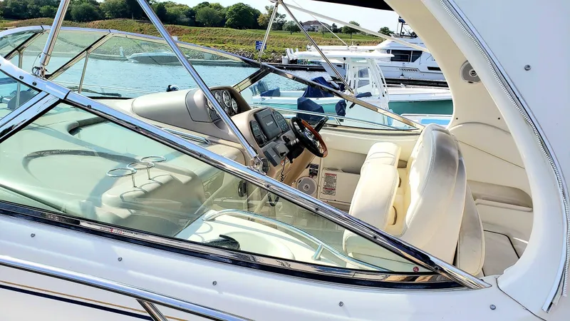 Slide: The Image of 2002 Sea Ray 300 Sundancer boat interior with steering wheel and seating, docked by the water. - 3