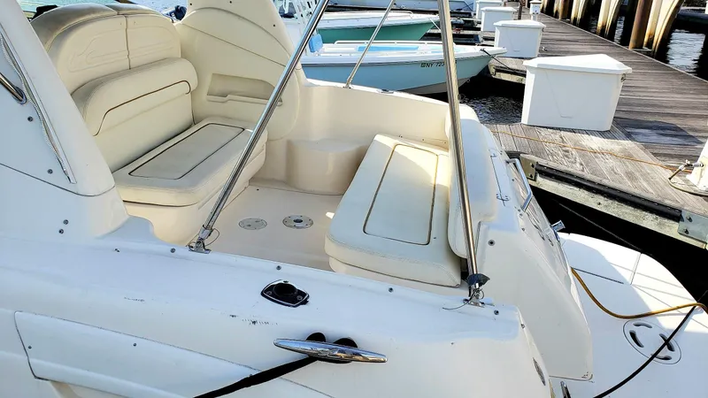 Slide: The Image of 2002 Sea Ray 300 Sundancer boat interior with white seating at a dock. - 9