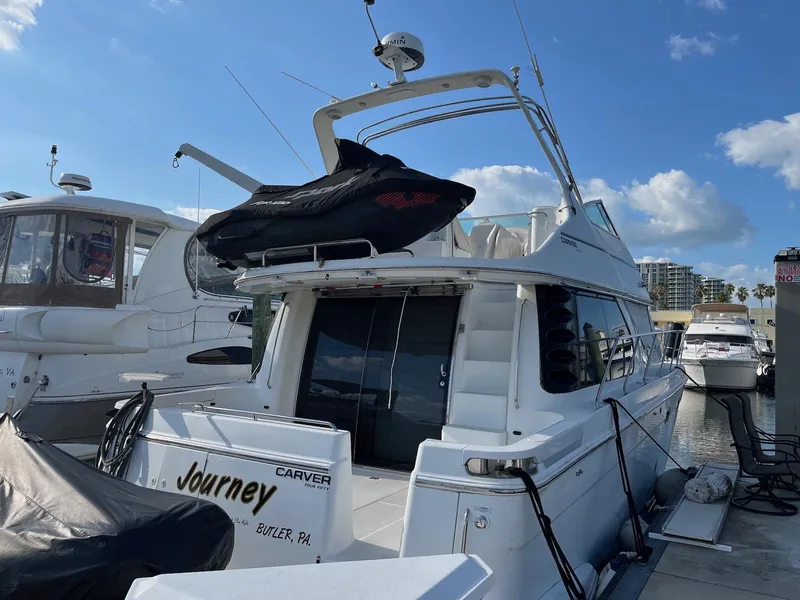 Slide: The Image of 1999 Carver 450 Voyager Pilothouse yacht docked at marina under clear blue sky. - 1