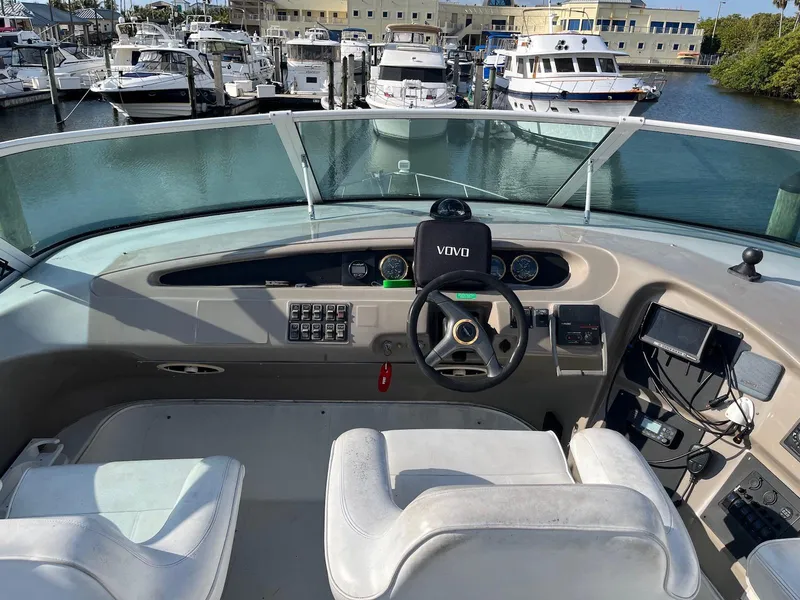 Slide: The Image of 1999 Carver 450 Voyager Pilothouse helm with marina view, featuring steering wheel and navigation equipment. - 2