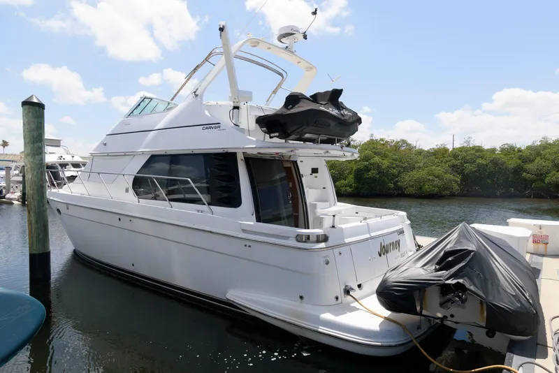 The Image of 1999 Carver 450 Voyager Pilothouse yacht docked at marina, clear sky background. - 0