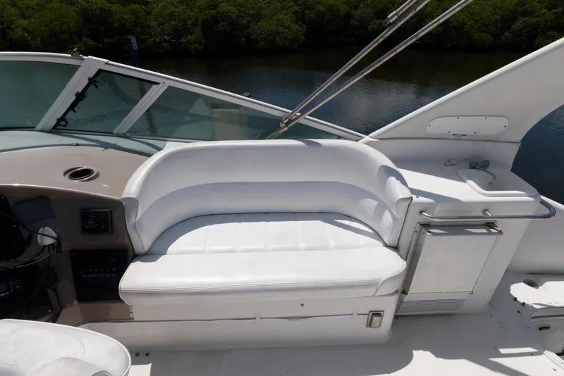 Slide: The Image of 1999 Carver 450 Voyager Pilothouse with white seating and helm, docked by water. - 7