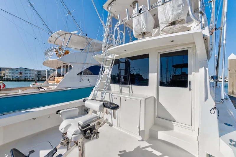 Slide: The Image of 1999 Viking 47 Convertible yacht with fishing equipment and ladder, docked in a marina. - 11