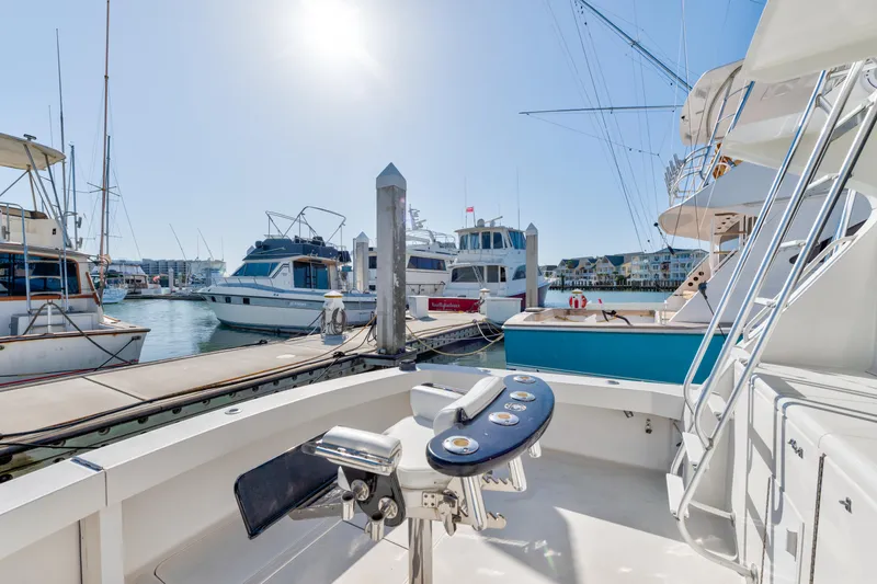 Slide: The Image of 1999 Viking 47 Convertible yacht docked at marina under bright sunlight. - 15