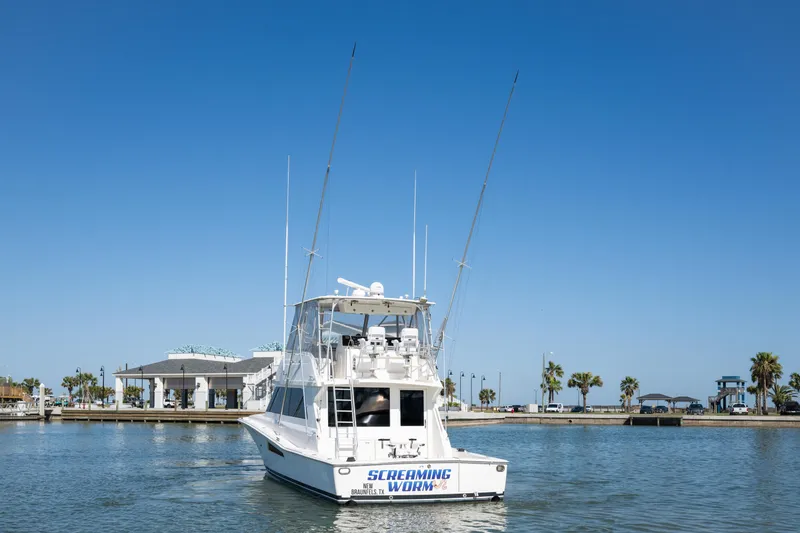 Slide: The Image of 1999 Viking 47 Convertible yacht on calm water under clear blue sky. - 3