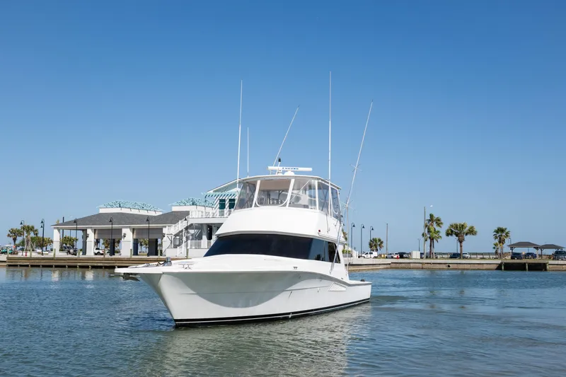 Slide: The Image of 1999 Viking 47 Convertible yacht on calm water near a marina. - 4