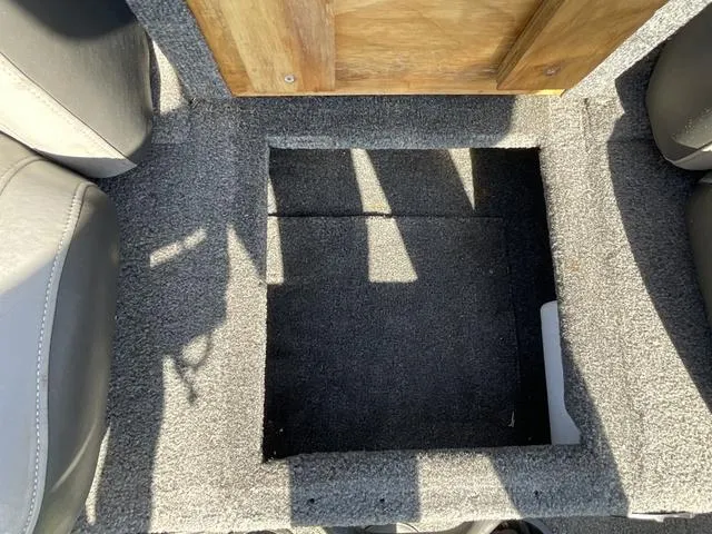 Slide: The Image of 2015 Tracker Pro 175 boat storage compartment with gray carpet and wooden lid. - 10