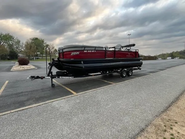 Slide: The Image of 2024 Regency 250 DL3 pontoon boat on trailer in parking lot under cloudy sky. - 13