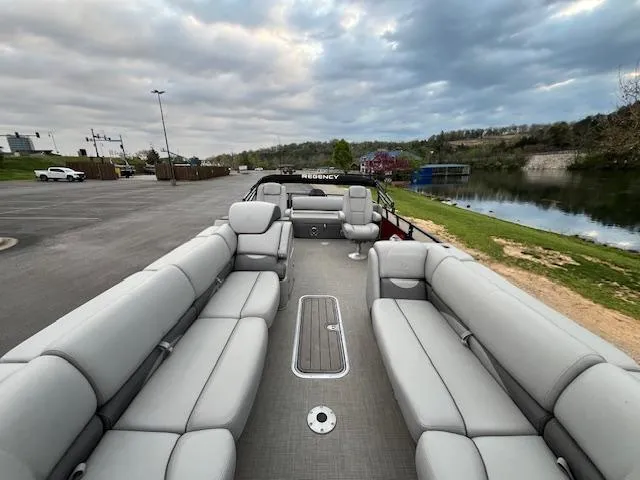 Slide: The Image of 2024 Regency 250 DL3 pontoon boat with spacious seating, docked by a serene lake. - 15
