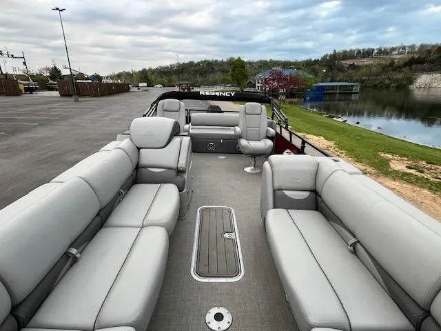Slide: The Image of 2024 Regency 250 DL3 pontoon boat with spacious seating, docked by a serene lake. - 16