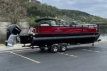 Slide: The Image of 2024 Regency 250 DL3 pontoon boat on trailer, parked near a scenic waterfront. - 4