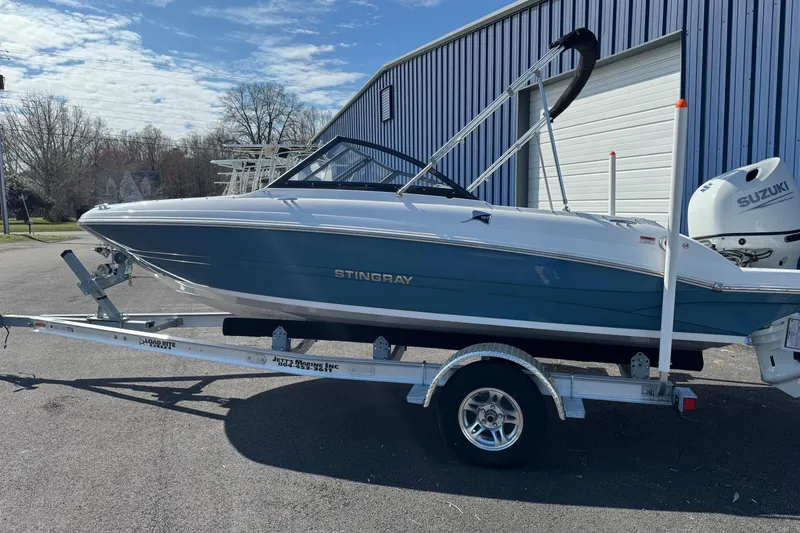 Slide: The Image of 2025 Stingray 191 DC boat on trailer, parked outside a blue building. - 10