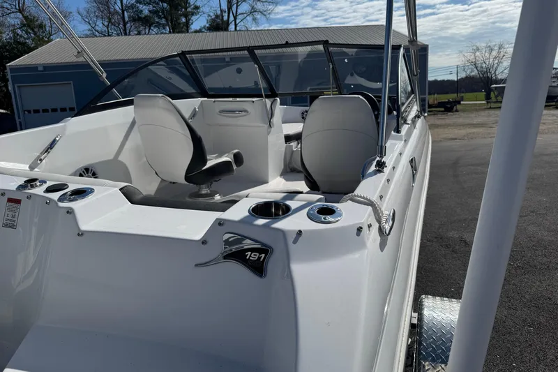 Slide: The Image of 2025 Stingray 191 DC boat interior with seating and cup holders, parked outdoors. - 8