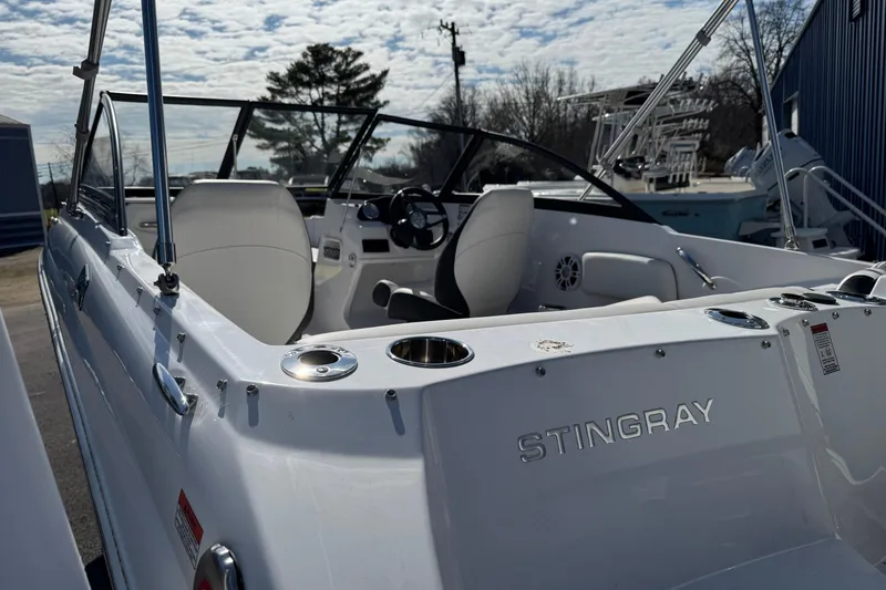 Slide: The Image of 2025 Stingray 191 DC boat interior with steering wheel and seating, under a partly cloudy sky. - 9