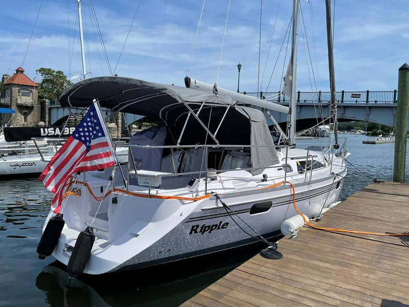 Slide: The Image of Catalina C355 sailboat docked, displaying American flag, with bridge in background. - 0