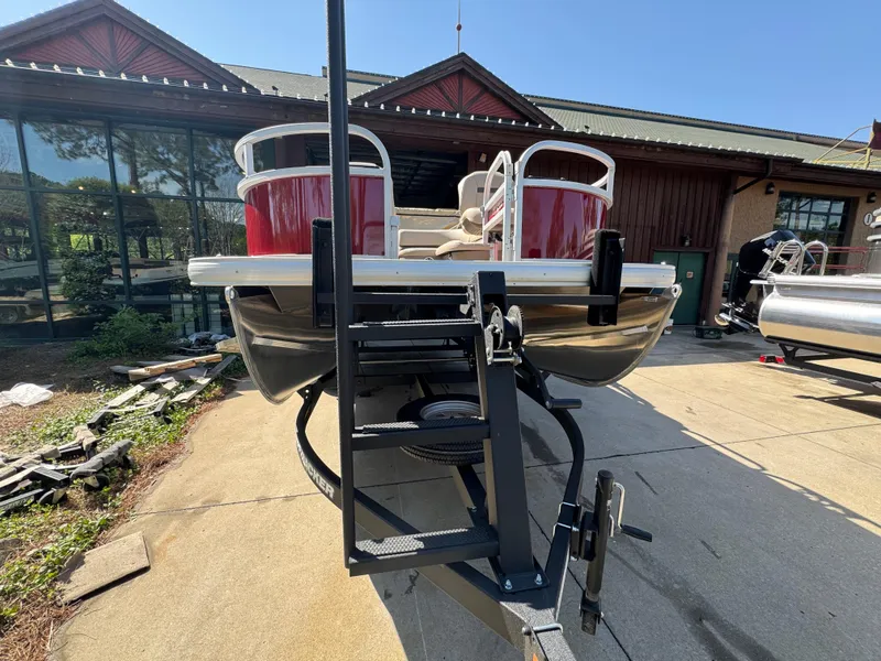 Slide: The Image of 2025 Sun Tracker Bass Buggy 16 XL Select pontoon boat on trailer, outdoor setting. - 2