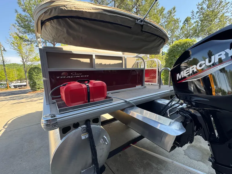 Slide: The Image of 2025 Sun Tracker Bass Buggy 16 XL Select pontoon boat with Mercury engine, docked outdoors. - 3