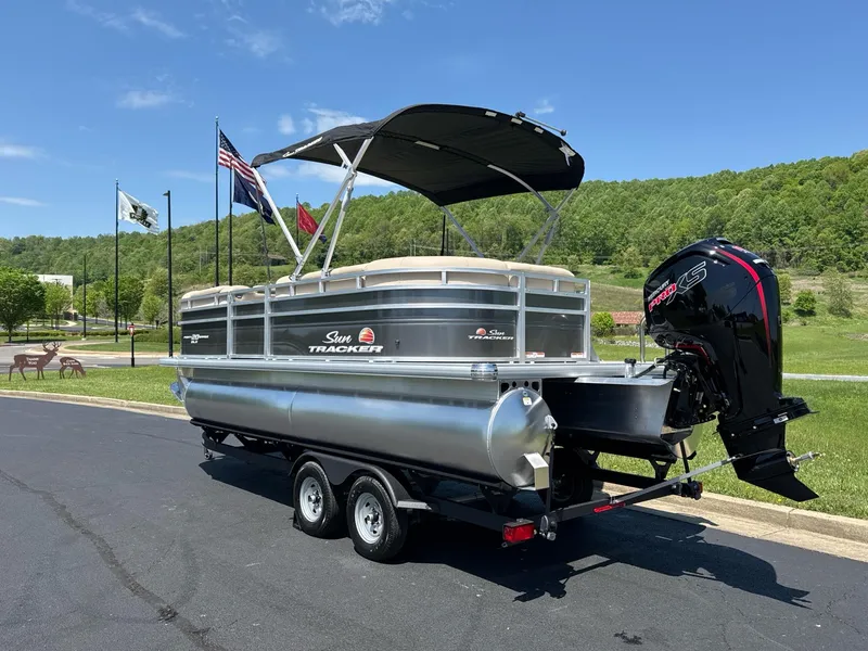 Slide: The Image of 2025 Sun Tracker Party Barge 20 DLX pontoon boat on trailer, parked outdoors. - 4