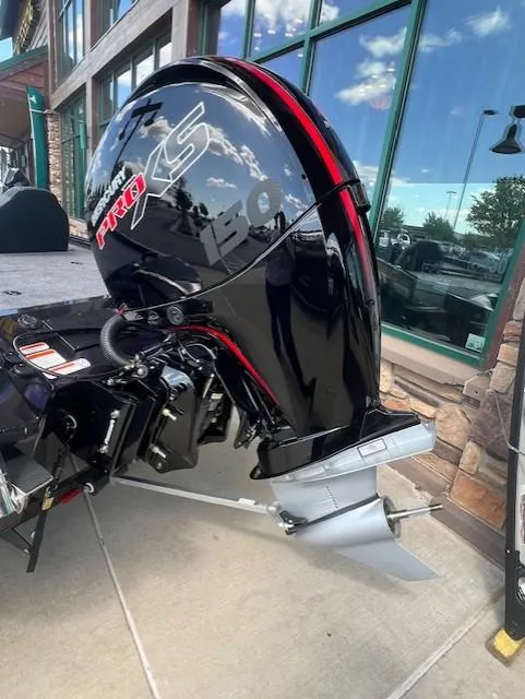 Slide: The Image of 2025 Tracker Savage 215 boat interior with steering console and seating, parked outdoors. - 2