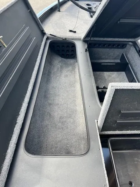 Slide: The Image of 2025 Tracker Savage 215 boat interior storage compartments with carpeted surfaces. - 6