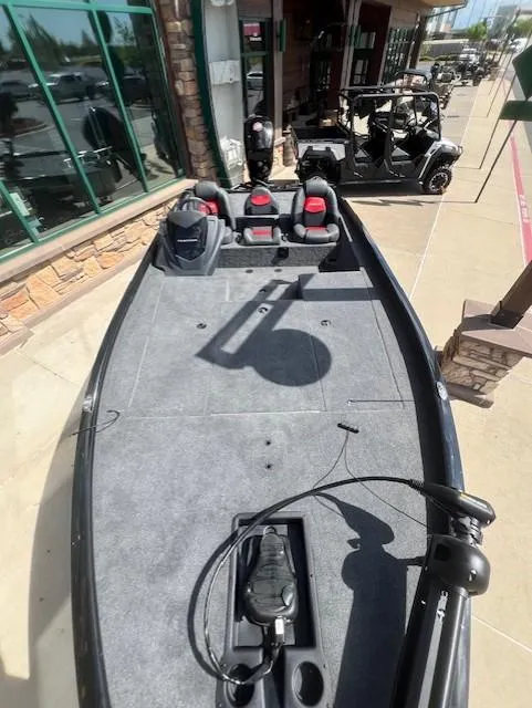 Slide: The Image of 2025 Tracker Savage 215 boat with spacious deck and modern seating, parked outdoors. - 9