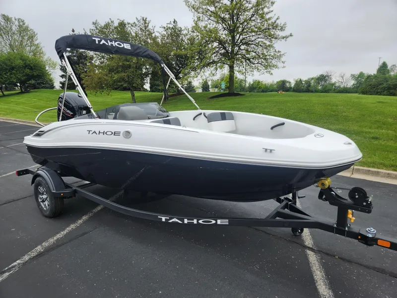 Slide: The Image of 2025 Tahoe T16 boat on trailer, parked outdoors with lush greenery background. - 0