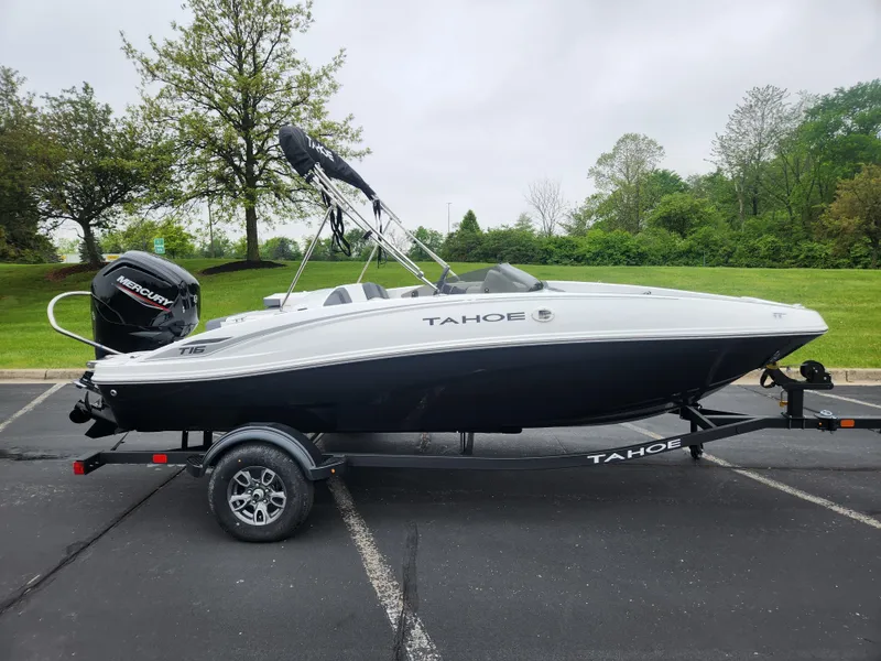 Slide: The Image of 2025 Tahoe T16 boat on trailer, parked outdoors, with lush greenery in the background. - 1