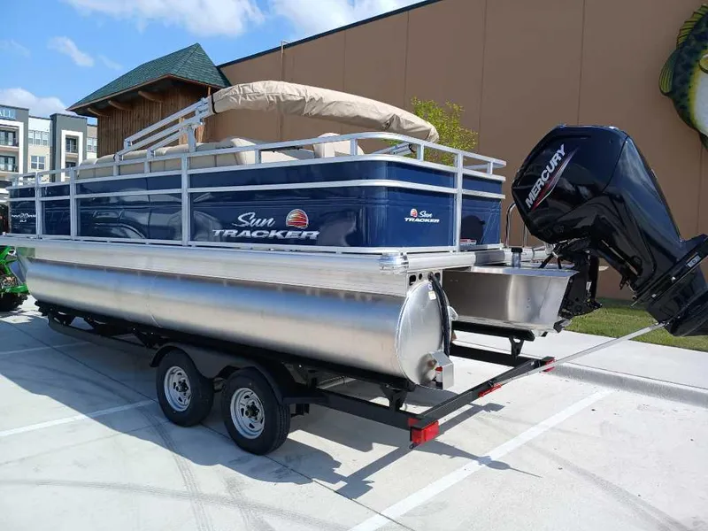 Slide: The Image of 2025 Sun Tracker Fishin' Barge 20 DLX pontoon boat on trailer, outdoor display. - 5
