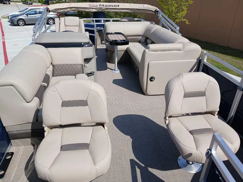 Slide: The Image of 2025 Sun Tracker Fishin' Barge 20 DLX interior with beige seating and table. - 7
