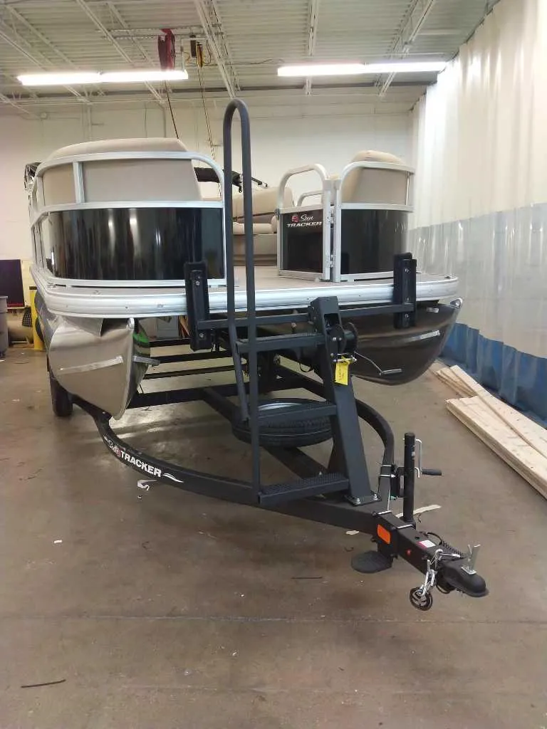 Slide: The Image of 2025 Sun Tracker Party Barge 16 DLX pontoon boat on trailer in a garage. - 2
