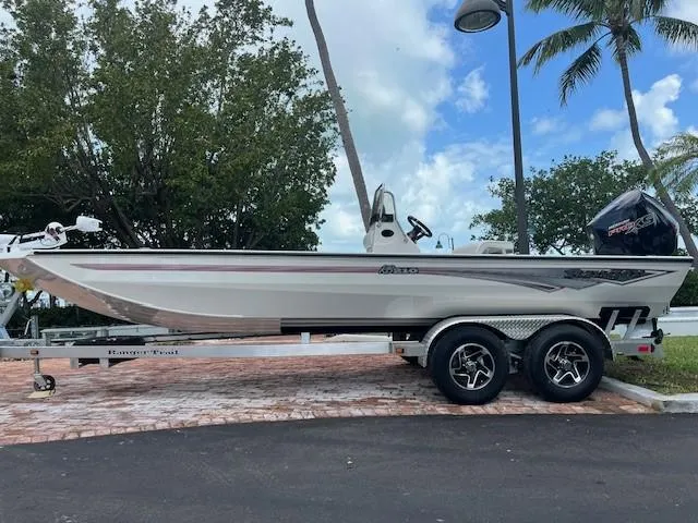 Slide: The Image of 2025 Ranger RB210 boat on trailer, parked outdoors on gravel, under clear blue sky. - 1
