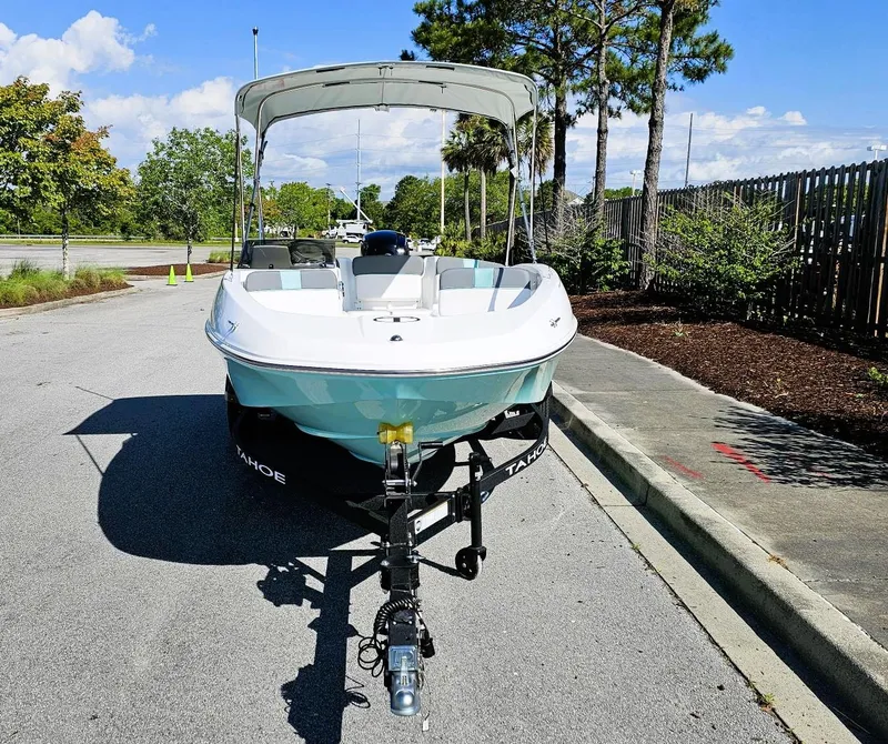 Slide: The Image of 2025 Tahoe T16 boat on trailer, parked on sunny street with trees in background. - 7