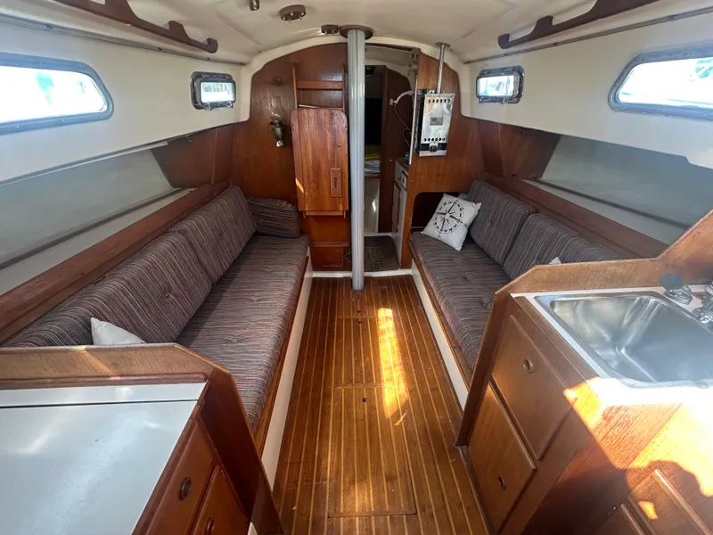 Slide: The Image of Interior of a 1981 Pearson 32 sailboat with wooden flooring and cozy seating. - 13