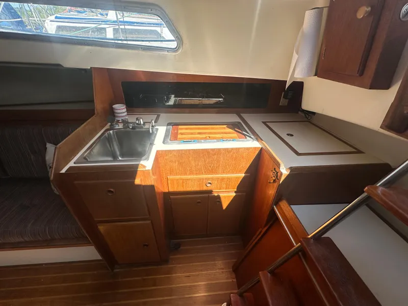 Slide: The Image of Interior of a 1981 Pearson 32 sailboat galley with wooden cabinetry and sink. - 14