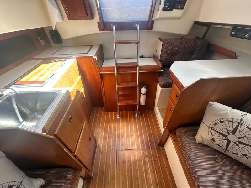 Slide: The Image of 1981 Pearson 32 sailboat interior with wooden flooring, compact kitchen, and seating area. - 15