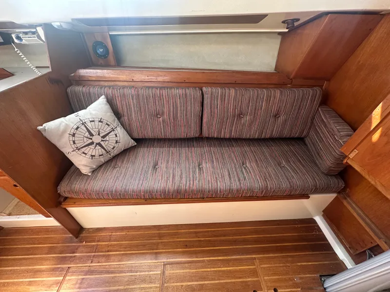 Slide: The Image of 1981 Pearson 32 sailboat interior with cushioned seating and compass-themed pillow. - 17