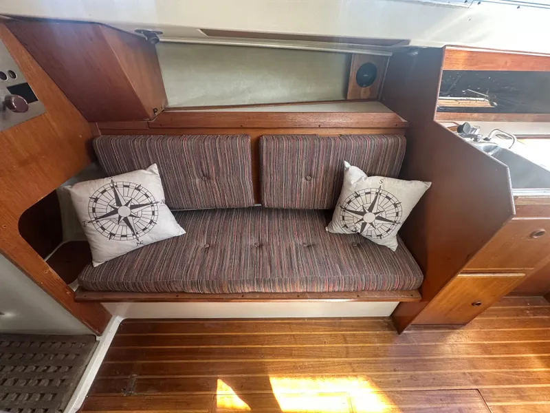 Slide: The Image of 1981 Pearson 32 sailboat interior with cushioned seating and nautical-themed pillows. - 18