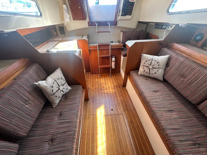 Slide: The Image of 1981 Pearson 32 sailboat interior with striped seating, wooden flooring, and nautical-themed pillows. - 19