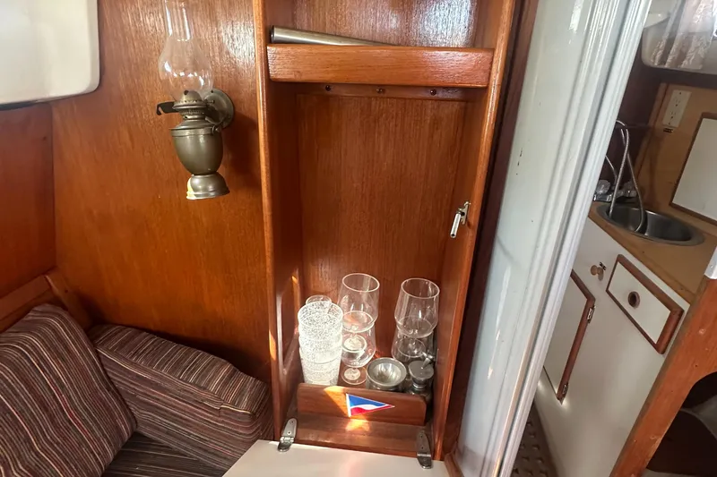 Slide: The Image of Cozy 1981 Pearson 32 yacht interior with wooden cabinetry and glassware storage. - 23