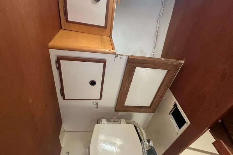 Slide: The Image of 1981 Pearson 32 sailboat bathroom with wooden cabinets and a compact toilet. - 26