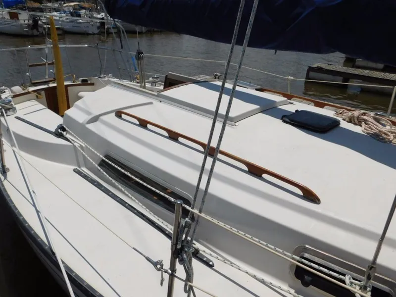 Slide: The Image of 1981 Pearson 32 sailboat deck with wooden handrails and rigging, docked at a marina. - 9