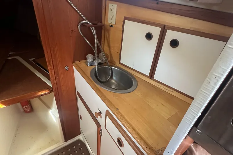 Slide: The Image of 1981 Pearson 32 yacht galley with wooden countertop, sink, and storage cabinets. - 24