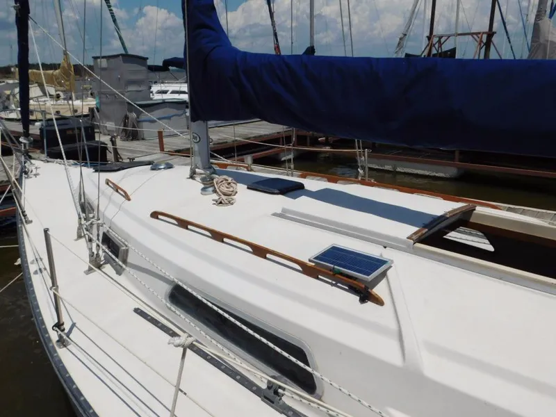 Slide: The Image of 1981 Pearson 32 sailboat docked, featuring a sleek white deck and blue sail cover. - 5